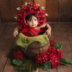 Seven-month-old Monishka in a beautiful red floral bonnet. The sitter stage is perfect for creative and colorful setups that showcase your baby's charm.
