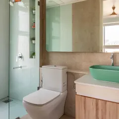 This bathroom combines soft blue tiles with earthy beige walls and a pop of color from the green vessel sink, creating a fresh and modern look.