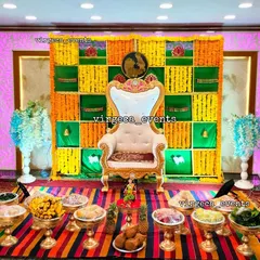 A vibrant Seemantham (baby shower) decor with a traditional backdrop of green and yellow marigold flowers in a checkerboard pattern.