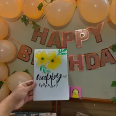 A handmade birthday card with watercolor yellow flowers and custom calligraphy, ready for a hostel birthday party.