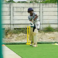 Ready for action at the crease. This young player is in his batting stance, focused and waiting for the next ball, showcasing the determination we instill in our trainees.
