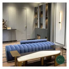 A vibrant blue channel-tufted sofa designed as the centerpiece for a modern apartment. The attached marble and wood bench offers a unique, integrated surface, blending functionality with a bold design statement.