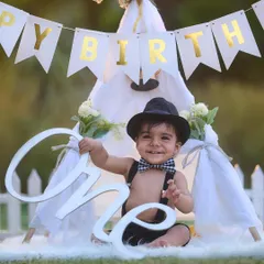 A big smile for the big ONE. Using props like this "One" sign and a classic teepee setup, I create timeless and joyful portraits to celebrate your baby's first birthday milestone.