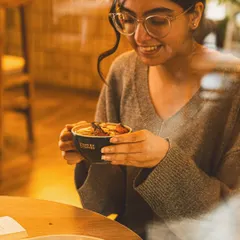 A lifestyle shot of a customer enjoying a warm drink in a cafe. Capturing genuine moments like this helps create a relatable and inviting brand image.