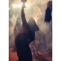 A woman lost in the moment during the Dhunuchi dance. The smoke and warm light create a divine, otherworldly atmosphere that is central to the Sandhya Aarti.