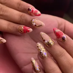 A bridal set fit for a queen. This design features a mix of intricate details on almond-shaped nails, including gold glitter, delicate pearls, 3D red bow embellishments, and a quilted pattern. It’s the ultimate in wedding day opulence.