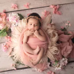 This little doll is wide awake and surrounded by soft pink blossoms. The floral elements perfectly complement her delicate features and pink swaddle.