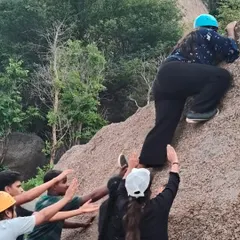 Teamwork makes the dream work. Students spot a fellow climber during a bouldering session, learning the importance of support and trust in a safe environment.