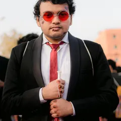 A cosplayer portrays a battle-worn Matt Murdock from Daredevil, complete with his red glasses and cane. The attention to detail in the costume and makeup is fantastic.