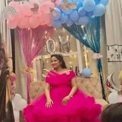A client looking radiant at her baby shower in a vibrant pink ruffled ball gown. This dress makes a statement for any celebratory event and is comfortable enough for expecting mothers.