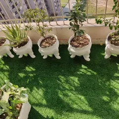 Details make the design. For this balcony, I used these unique foot-shaped planters to add a touch of personality, placed on high-quality artificial turf to create a playful and green corner.