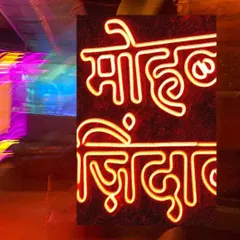 A close-up of a Hindi neon sign, 'Mohabbat Zindabad', against a backdrop of blurred party lights. This shot captures the poetic and chaotic energy of Delhi's nightlife.