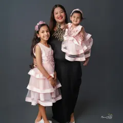 A trio of grace, giggles, and glam. This beautiful portrait of a mother with her two daughters, all dressed in lovely pink, is a testament to their special bond.