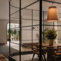 The glass-walled conference room sits at the heart of the showroom, blending privacy with a sense of openness. The transparency allows light to flow, while a textured carpet and large pendant lamps define the area, creating a chic and functional meeting space.