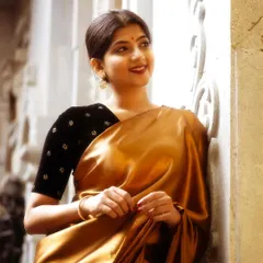 A smiling portrait in a shimmering gold satin saree. The focus is on creating a radiant and approachable look, letting the saree's luxurious texture speak for itself.