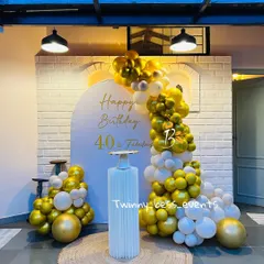 A sophisticated setup for a 40th birthday. This design features a white arched backdrop against a brick wall, with a beautiful gold and white balloon cascade for an elegant and modern look.