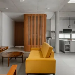 The living area of the LUCID residence showcases our minimalist approach using a humble material palette. Exposed concrete ceilings and vitrified tile floors create a neutral backdrop, punctuated by a custom wooden screen that separates the foyer.