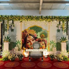The divine beauty of this Krishna-themed backdrop is captivating. It was curated with so much love for a baby shower, featuring Yashoda and Krishna, and framed with greenery and hanging bells.