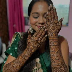 Another happy bride, her eyes closed in a moment of bliss. Her hands are adorned with a full, intricate bridal design featuring beautiful rose motifs.
