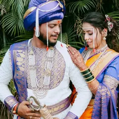 A classic portrait of a Maharashtrian couple against a lush green backdrop. The vibrant colors of their outfits and the natural setting create a beautiful contrast.