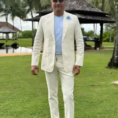 A client looking effortlessly stylish in a custom off-white linen suit. This look is perfect for a daytime event or a destination wedding, offering relaxed elegance.