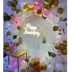 A closer look at the anniversary ring backdrop, showing the details of the balloon arrangement and the hanging birdcage props that add a whimsical touch to the celebration decor.