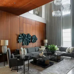 The double-height living room in this contemporary home uses expansive glass and soaring curtains to create a sense of grandeur. I balanced the scale with warm wood paneling and a monochromatic palette to keep the space inviting and elegant.