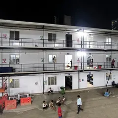A ground-level view of the G+2 labour colony at night, with residents relaxing in the courtyard. We focus on creating not just buildings, but comfortable communities for the workforce.