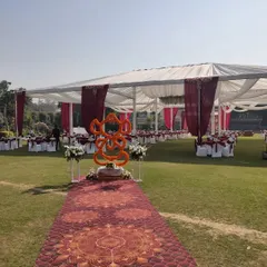 An entrance pathway for an outdoor wedding, featuring a marigold Ganesha idol for blessings. The path leads to a large tent with guest seating, showing how I plan the entire guest journey from entry to the main area.