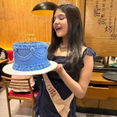 A beautiful young lady celebrating her birthday with a custom vintage style cake. The delicate blue piping and draping details were designed to match her elegant party dress.