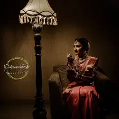 An artistic shot capturing the elegance of a bride before her ceremony. The warm lighting highlights the golden tones in her makeup and the rich texture of her silk saree.