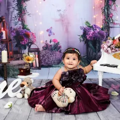 A wider view of the enchanting purple piano set. The soft lighting and fairytale-like background elements come together to create a truly memorable first birthday photograph.