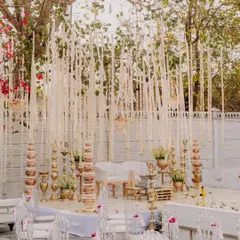 The beautiful wedding mandap, decorated with hanging white florals and traditional brass elements, ready for the ceremony.