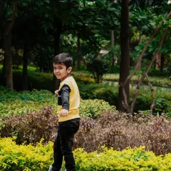 Capturing a child's playful energy as he looks back with a smile during our outdoor photoshoot in a lush Bangalore park.