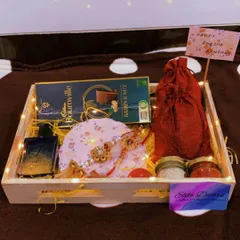 This is a classic Rakhi hamper for a brother, featuring a bottle of perfume, a bar of Cadbury Bournville, a beautiful rakhi, and traditional roli chawal pots, all lit up with warm fairy lights.