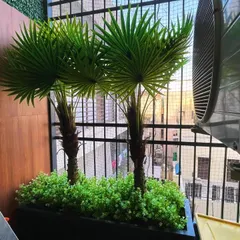 For this small balcony, we used a large planter with artificial palm trees to create a tropical vibe. This is an effective way to add significant greenery and create a focal point without permanently altering the walls.