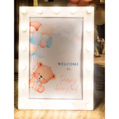 A 'Welcome to Pari's Bear-y Land' sign, framed with marquee lights, creates a warm and inviting entrance for a teddy bear-themed party.
