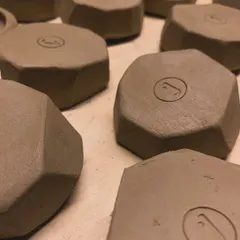A collection of geometric, faceted pieces, each stamped with my logo. This is a glimpse of a new collection in the making, seen here in its raw, unglazed form.