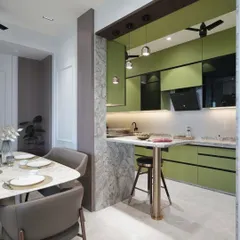 An open-concept view showing how the sage green kitchen integrates with the dining area. The marble-clad pillar and breakfast bar create a natural, stylish division between the spaces.