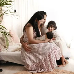 A candid moment from a family newborn session. The older sister looks on with love as her parents cradle the new baby, all in a comfortable, lifestyle setting.