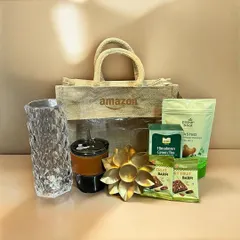An eco-friendly Diwali gift option for Amazon, featuring a branded jute bag filled with healthy snacks, a decorative tea light holder, and a custom tumbler.