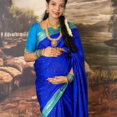 Embracing tradition and elegance. This studio maternity photo captures the timeless beauty of a mother-to-be in a stunning blue silk saree, adorned with traditional jewelry and flowers.