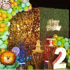 A closer look at the safari party backdrop, showing the contrast between the sparkling gold shimmer panel and the lush green wall. The neon "Happy Birthday" sign adds a modern touch.