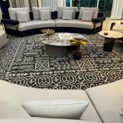 This living area is defined by its unique circular layout, featuring two curved sofas facing each other over a striking patterned rug. This arrangement fosters connection and conversation, making it a perfect setup for families who love to entertain.