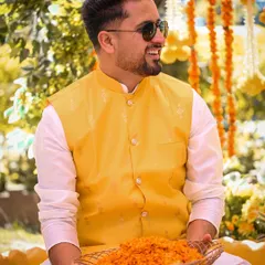 The groom enjoying a lighthearted moment during his Haldi ceremony, holding a basket of marigold petals.