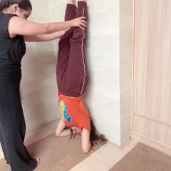 Using a wall is a fantastic way to build confidence in inversions. Here, I'm providing support to a student, helping her find the correct alignment and stability in a wall assisted headstand.