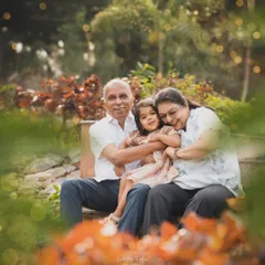 A granddaughter wrapped in a warm hug between her grandparents on a park bench. I focus on capturing these priceless, multi-generational bonds that form the legacy of a family.
