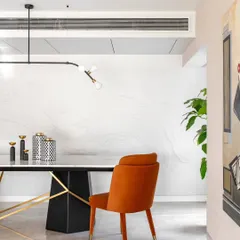 A detail from the Evelyn duplex, this view highlights the flow between spaces. The bold orange dining chair adds a pop of color against a custom wall with subtle, wave-like textures, creating a sense of movement and artistry that connects the dining and living areas.
