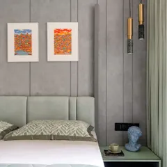 This contemporary bedroom uses a cool, neutral palette to create a calming environment. The paneled grey wall adds subtle texture, while pops of color from the artwork and the mint green bedside table bring a touch of personality. Marble and brass pendant lights add a final touch of elegance.
