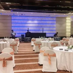 We manage the complete setup for corporate seminars and galas, ensuring a flawless layout. This view shows the ballroom at Radisson Blu, Bangalore, prepared for a business event, with organized seating, clean table arrangements, and stage tech ready for the program.